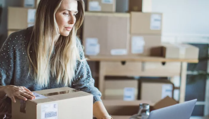 Woman on computer with moving boxes in the background